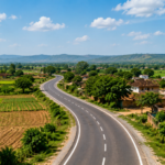 A newly paved road winds through an Indian village surrounded by farms and houses, representing improved rural connectivity and access to markets and services.