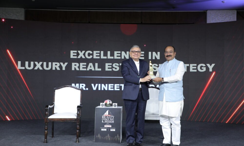 A presenter hands an award to a recipient on stage at the ET Now Realty Conclave & Awards 2026, with the backdrop highlighting excellence in luxury real estate strategy.