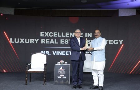 A presenter hands an award to a recipient on stage at the ET Now Realty Conclave & Awards 2026, with the backdrop highlighting excellence in luxury real estate strategy.