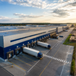 Modern logistics warehouse with trucks loading goods at a large industrial park in India.